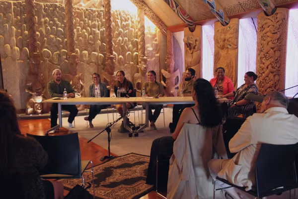 Group sitting inside a meeting house on a marae.