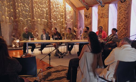 Group sitting inside a meeting house on a marae.