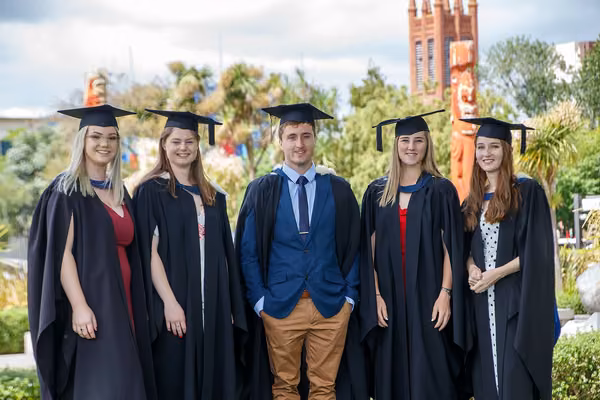 Group of five science students standing wearing graduation attire