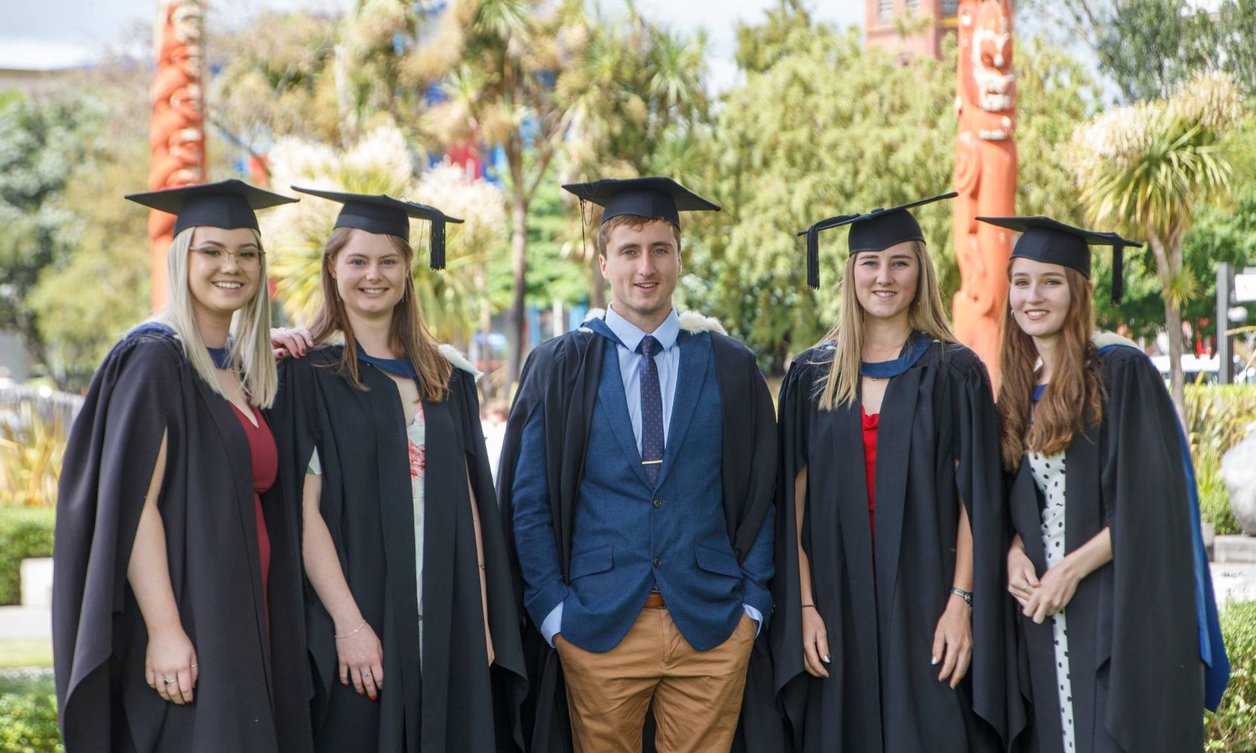 Group of five science students standing wearing graduation attire