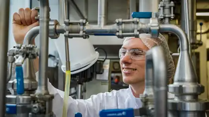 Smiling person in lab coat operates a machine