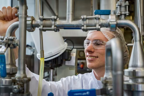 Smiling person in lab coat operates a machine