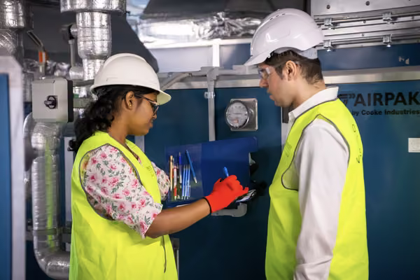a man and a woman in hard hats and fluro vests look at document