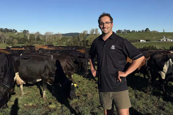 man standing in field with cows behind him