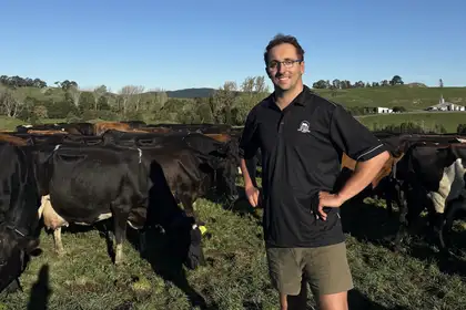 man standing in field with cows behind him