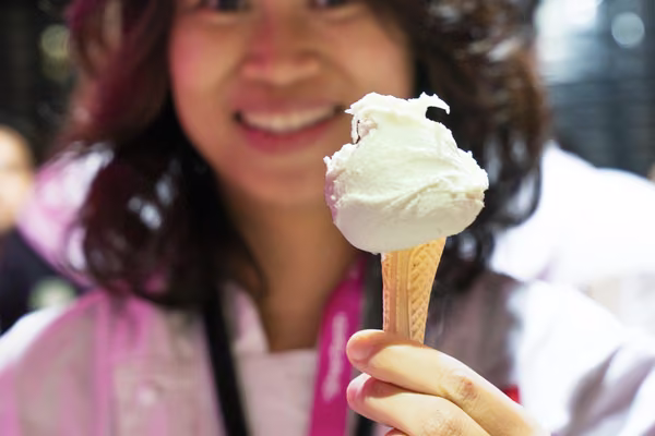 woman blurred in background, focus on gelato she's holding out to camera
