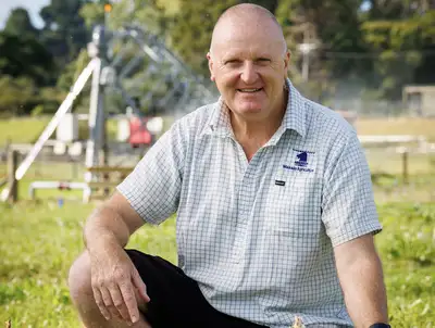 man kneeling in a field smiling at camera