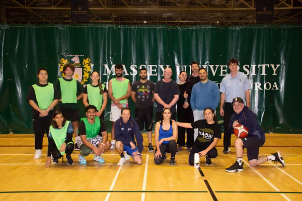 group of staff and students standing on court smiling