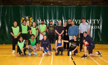 group of staff and students standing on court smiling