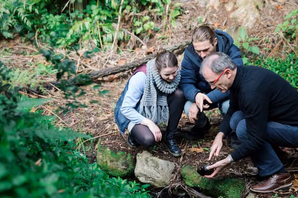 Three people examine a river stone