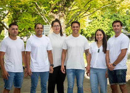 Group of six people of the Te-Rau-Tauawhi team standing outside, all wearing white t-shirts and denim pants