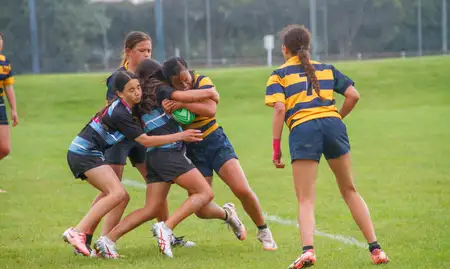 School girls playing rugby sevens on a field