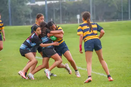 School girls playing rugby sevens on a field