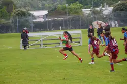 girl running across field with rugby ball under arm