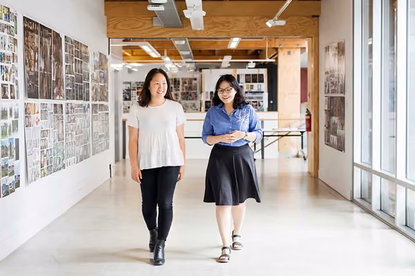Two smiling people walk through a project gallery