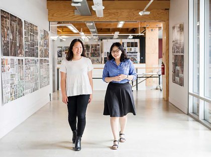 Two smiling people walk through a project gallery