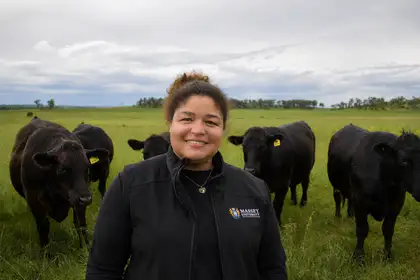 woman smiling at camera surrounded by cows