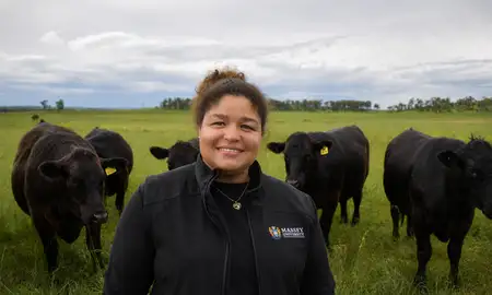 woman smiling at camera surrounded by cows