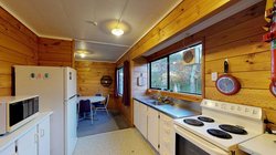 Interior of Atawhai Flats kitchen with table and chairs, fridge, bench, sink and oven