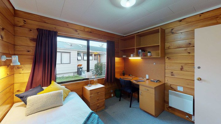 Interior of Atawhai Flats single bedroom with bed, drawers, and built-in furniture