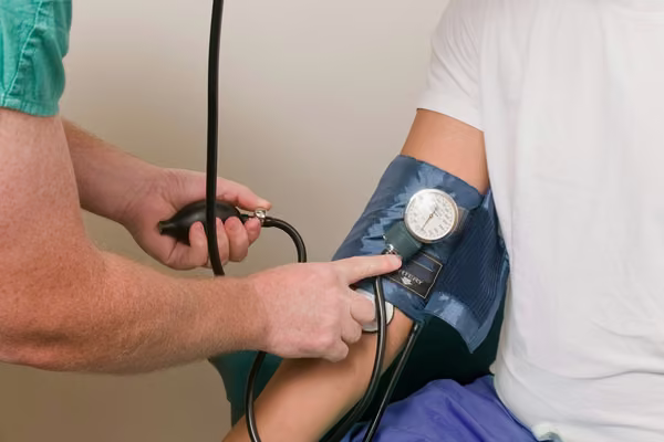 Arm with blood pressure cuff on and another arm holding a stethoscope