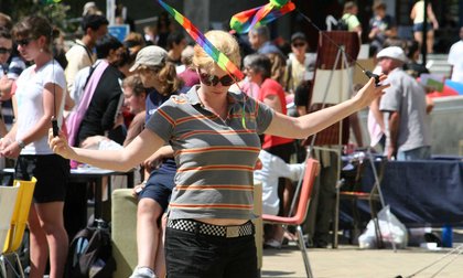 Student twirling two narrow rainbow flags, with a crowd of students in the background