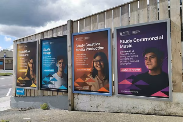 Posters with students and marketing compaign to 'create with us' on an outside wall.