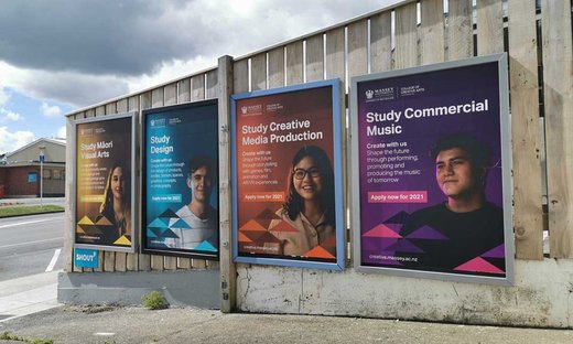 Posters with students and marketing compaign to 'create with us' on an outside wall.