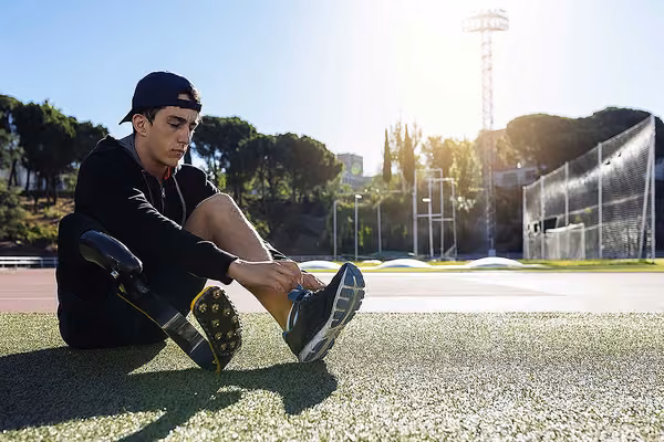 Person with a prosthetic leg, sitting down lacing up his sneaker