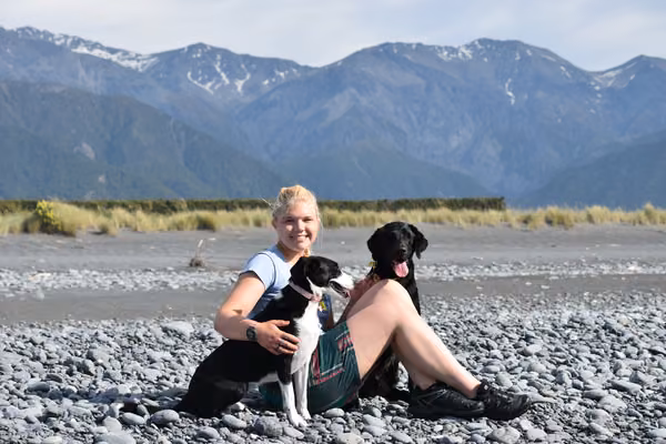 girl sitting with two dogs in front of mountain range