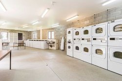 Interior of Kairanga and Rotary Courts large laundry with tables and multiple washing machines