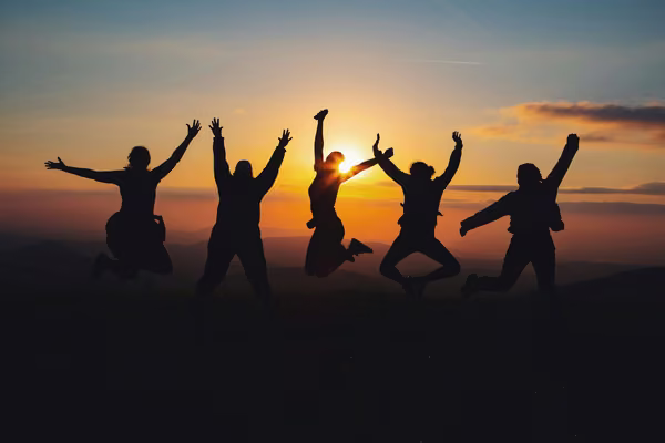 group of people jumping in front of a sunset