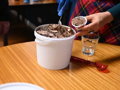 A person is scooping out ice cream from a tub.