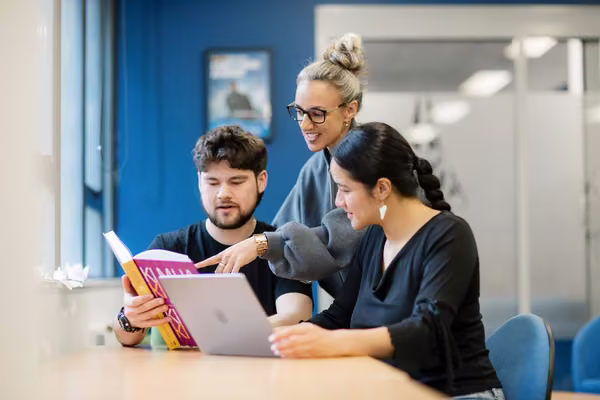 Two students being helped by an academic adviser