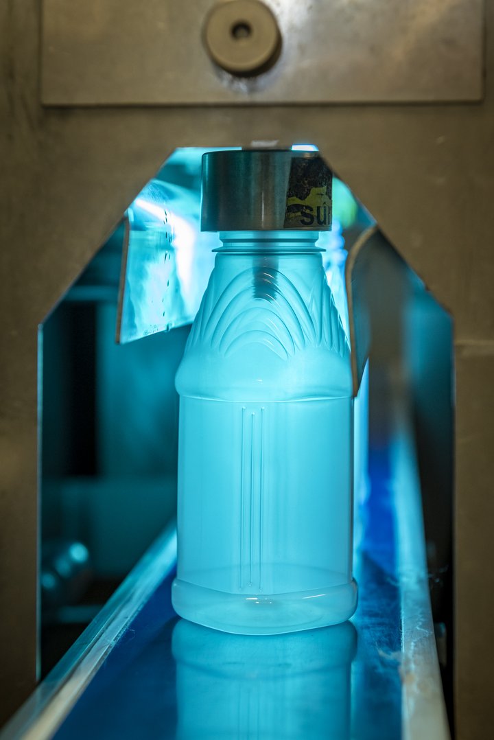 Glowing blue bottle inside a machine.