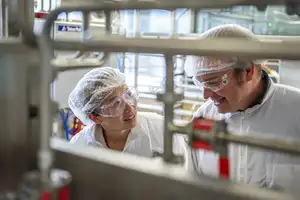 Woman and man talking to each other and smiling, behind machinery.