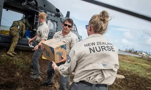 Members of the New Zealand Defence Force unloading supplies from a helicopter.