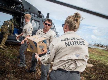 Members of the New Zealand Defence Force unloading supplies from a helicopter.
