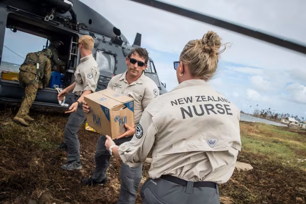 Members of the New Zealand Defence Force unloading supplies from a helicopter.