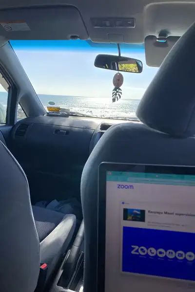 Laptop being used for study in the back of a car looking out at the ocean